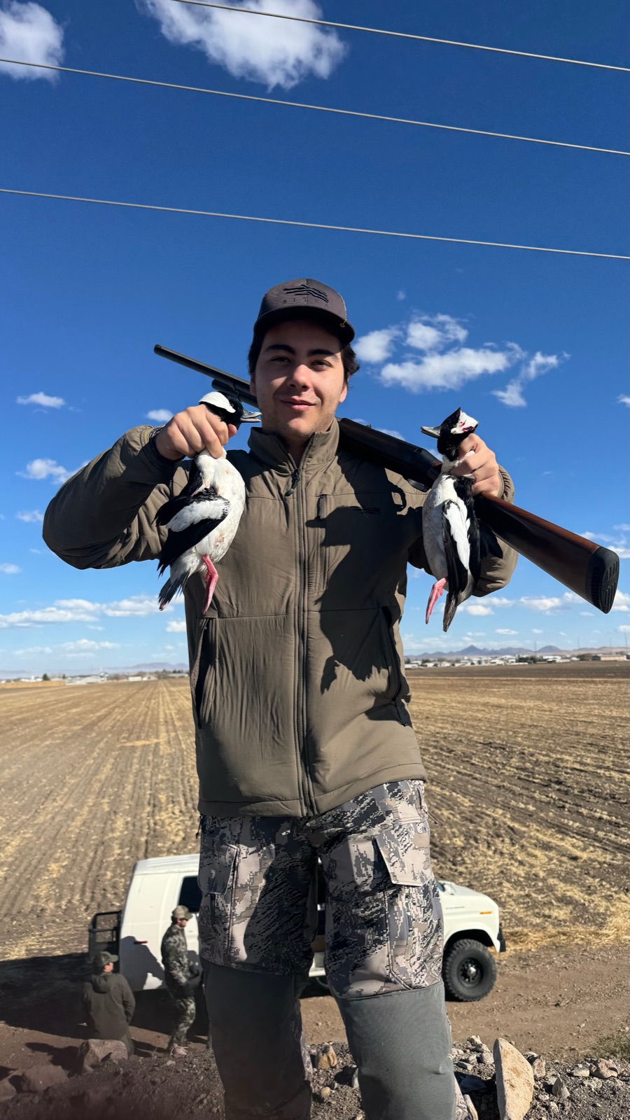 Hunter with white-winged dove pair under cloud-scattered Chihuahua sky